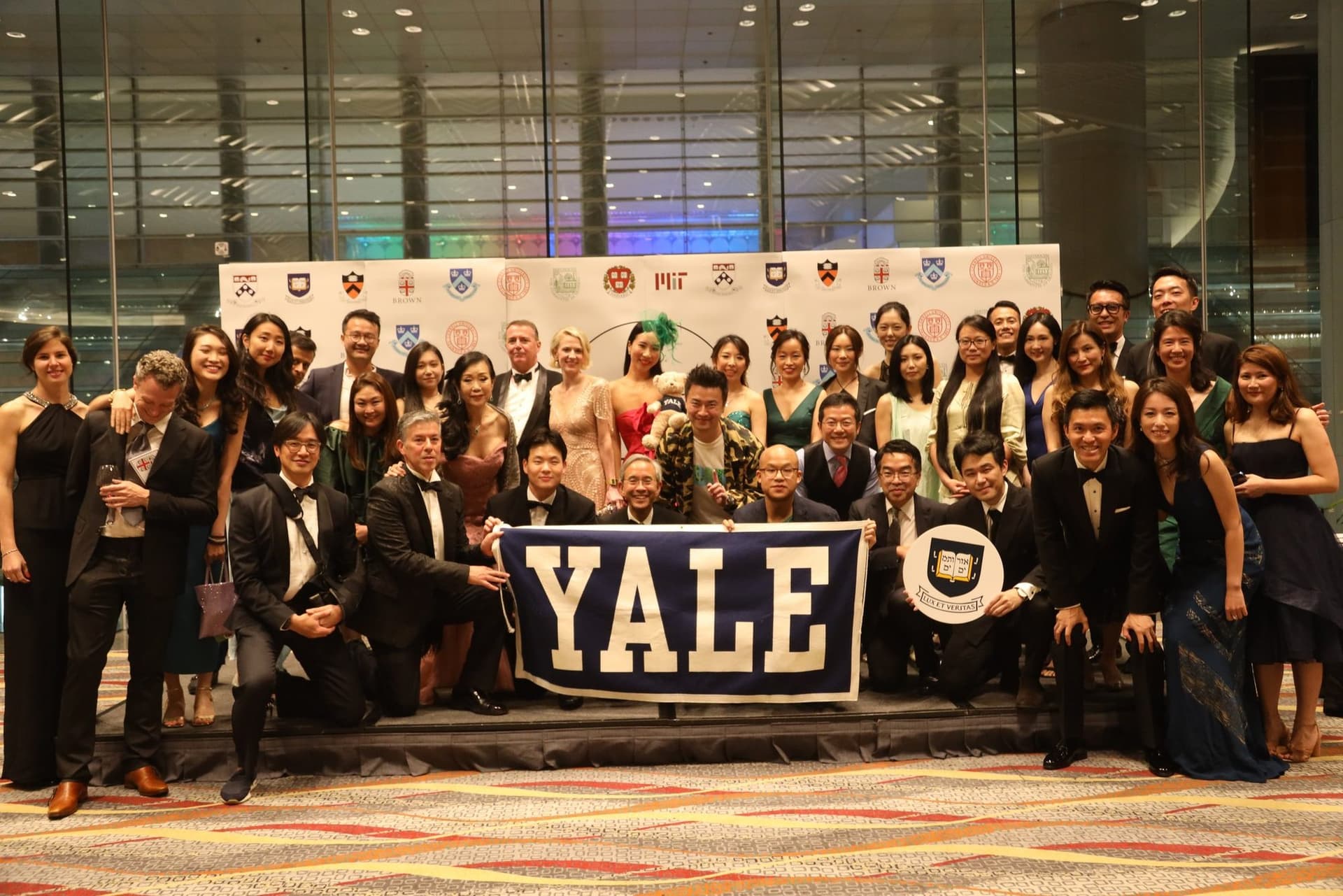 Yale alumni in black tie at the Ivy Ball in Hong Kong, holding a Yale banner