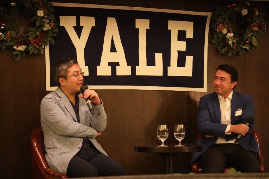 Two speakers in conversation beneath a Yale banner