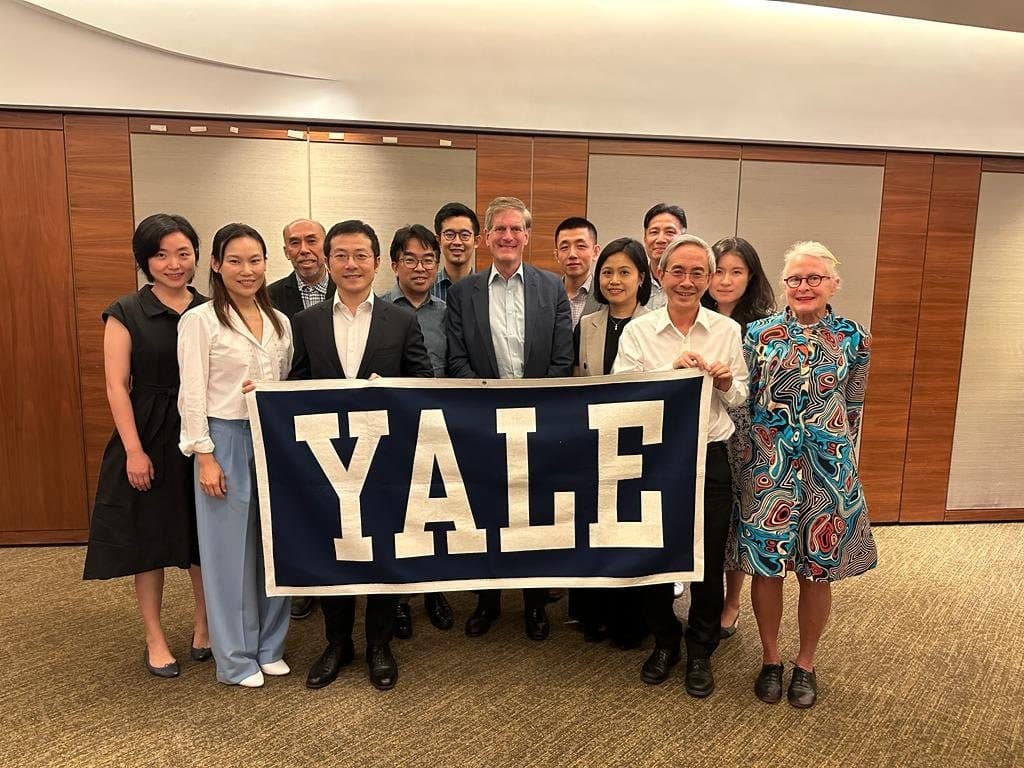 Members photographed with a Yale banner after a speaker event