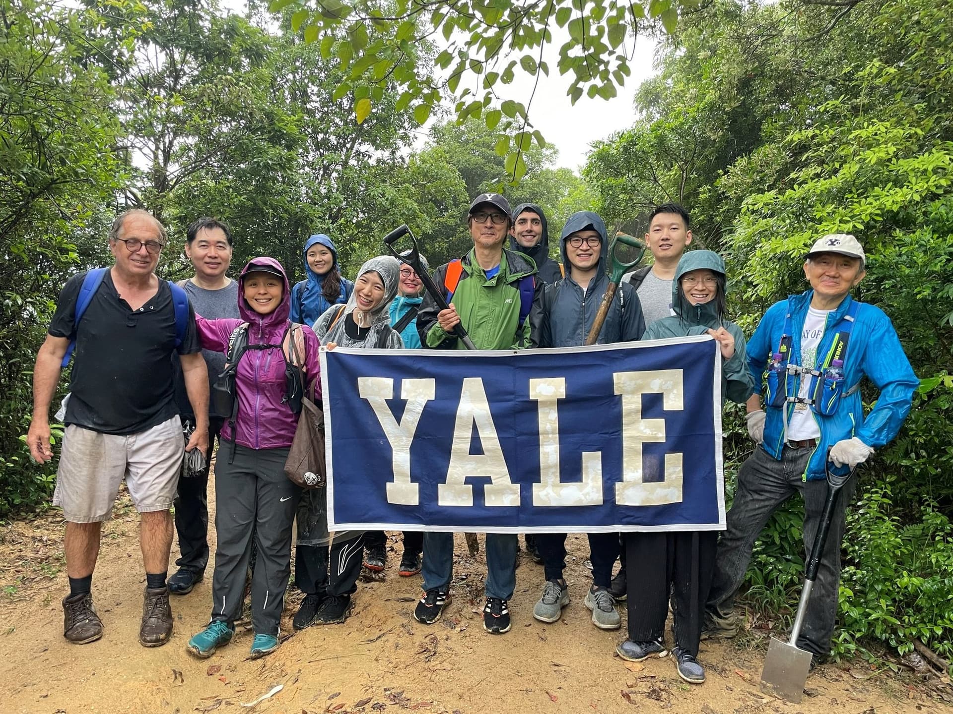 Volunteers with a Yale banner and shovels at the Lantau tree planting