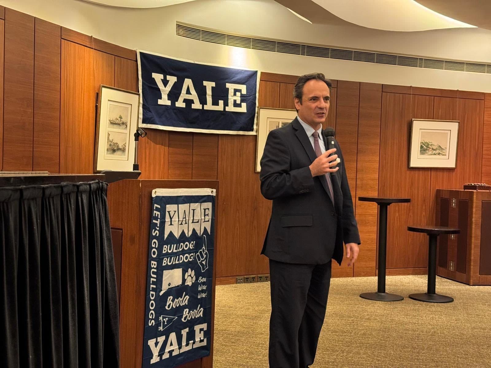 A Yale dean addressing Yale Club of Hong Kong members beneath a Yale banner