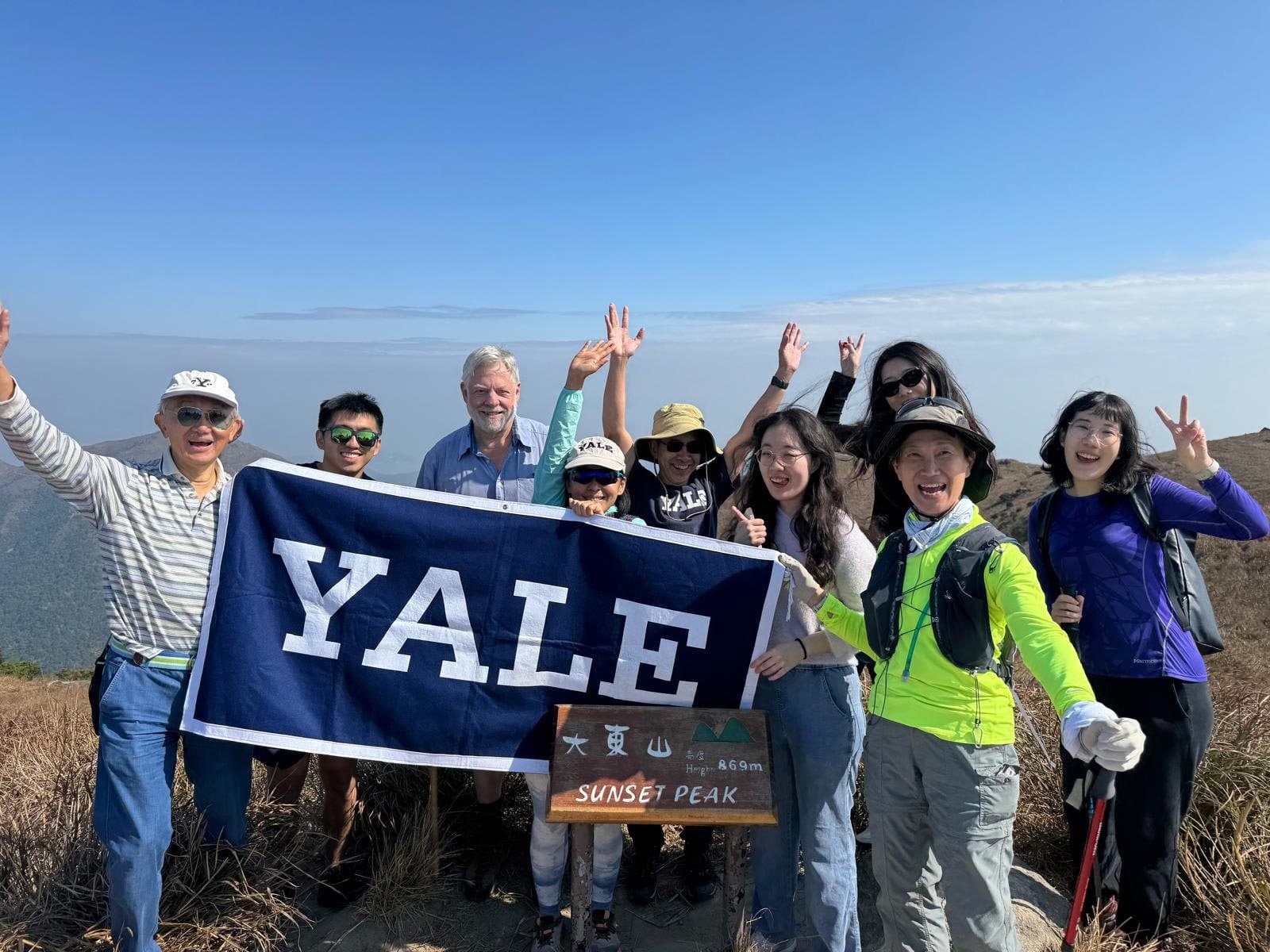 Club members holding a Yale banner at the summit of Sunset Peak on Lantau